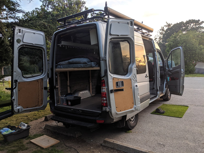 Open doors showcase this RV rental's custom Sprinter van conversion & comfy camp setup at sunset. — photo 7