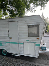 Vintage Aristocrat Land-Commando travel trailer with teal stripes, great for an RV rental adventure.