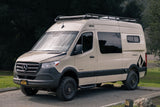 Light tan custom Mercedes Sprinter camper van, equipped for off-road adventures with a roof rack. Ideal for an RV rental.