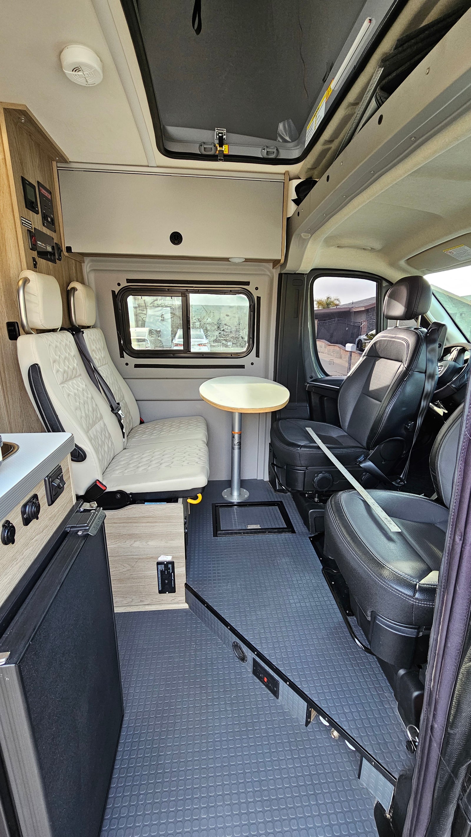 Inside a modern RV rental: kitchen, comfortable passenger seating, and dining table. Ideal for compact travel.