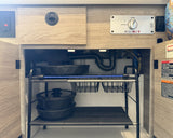 Inside an rv rental: kitchen cabinet with eco-HOT water heater panel, sink plumbing, and organized pot/pan storage.