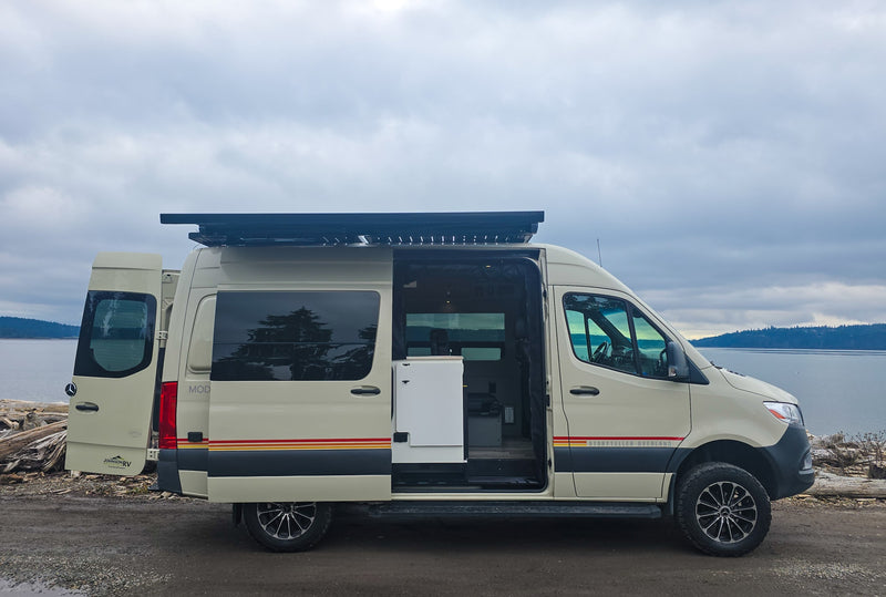 Tan Mercedes Sprinter camper van parked by the water. An ideal rv rental for coastal adventures and exploration. — photo 1