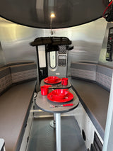 Experience comfort in this rv rental interior, featuring a cozy dining area with bright red place settings & plush booth seating.