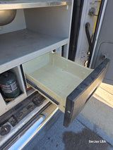 RV rental interior: open storage drawer, sink, shelving, and propane tank visible in this mobile kitchen setup.