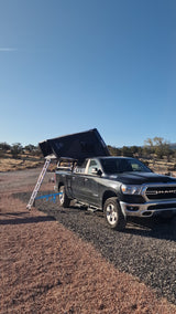 Black Ram pickup truck with iKamper rooftop tent and ladder on gravel. Perfect setup for an rv rental camping trip.