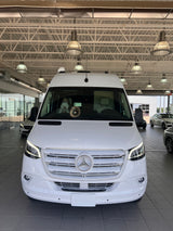 White Mercedes-Benz Sprinter van, ideal for rv rental, with a person and dog inside at a dealership.