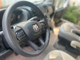 Interior of a Ram van or RV rental, focusing on the steering wheel with its distinctive logo and control buttons.