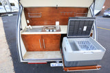 A convenient rv rental outdoor kitchen featuring a sink, two-burner stove, cabinetry, and a pull-out refrigerator.