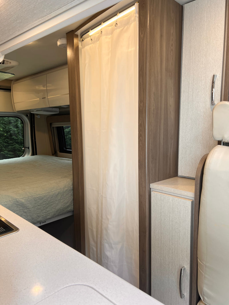Cozy RV rental interior: a bed, shower curtain, kitchen counter, and storage maximize space for travel adventures. — photo 8