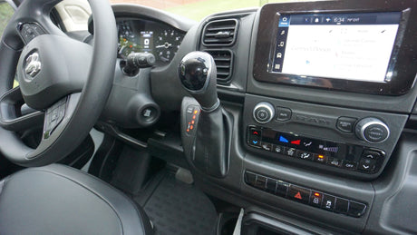 Inside an RV rental, this Ram ProMaster dashboard features an infotainment screen, gear shifter, and climate controls.