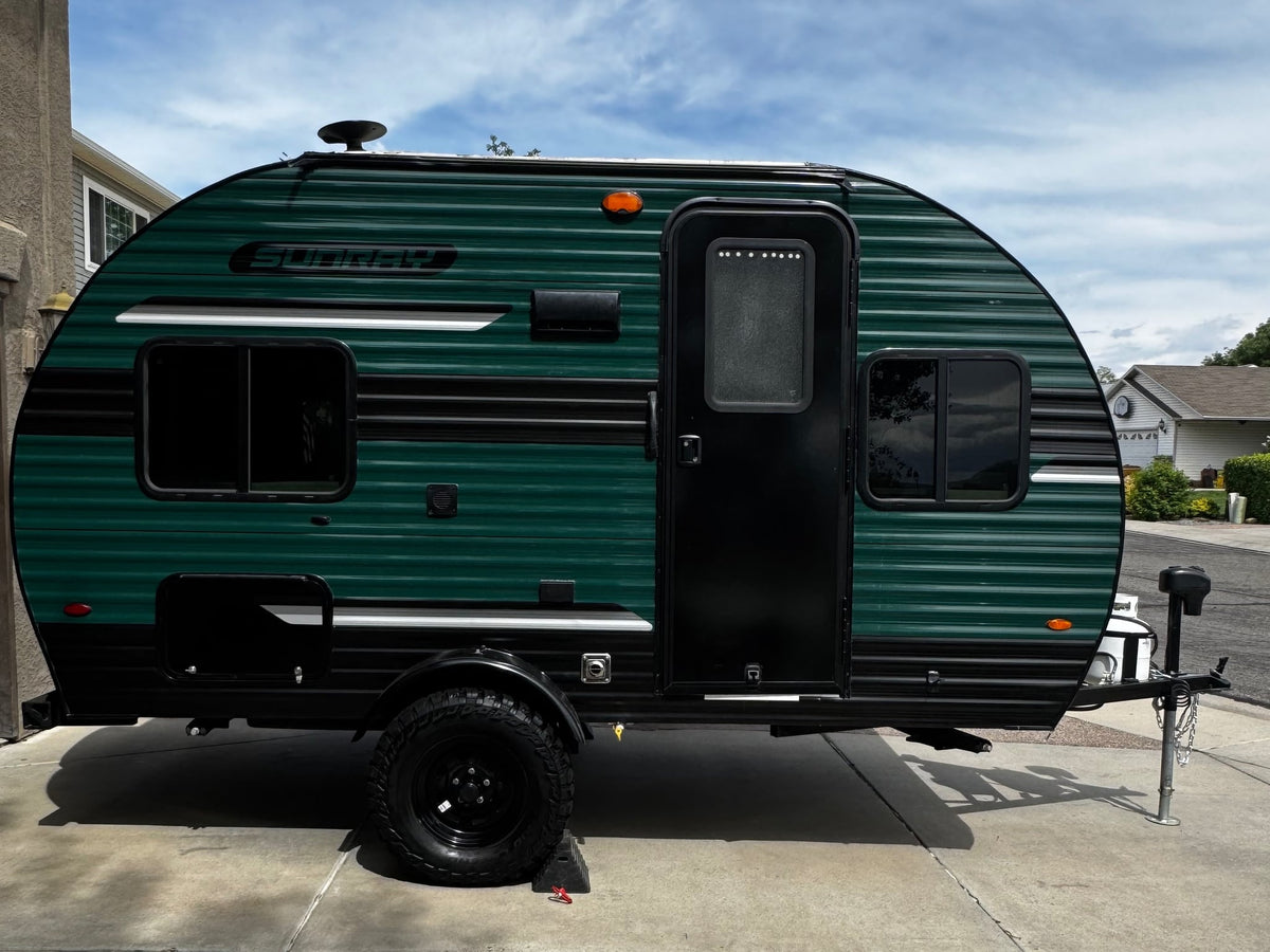 Green Sunray travel trailer ready for adventure. Perfect for an RV rental to explore the great outdoors.|Vibrant green travel trailer with steps and open door