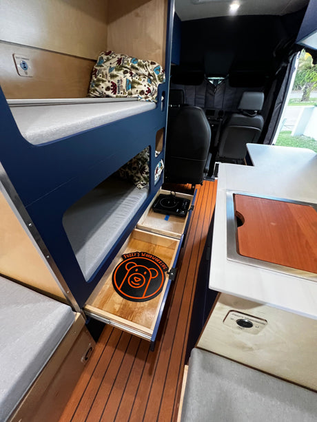 Inside a compact rv rental, a bunk bed setup, pull-out induction burner, and storage drawers maximize space.