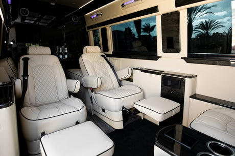 Luxury RV rental interior with plush white leather captain's chairs, footrests, and premium amenities for ultimate comfort.