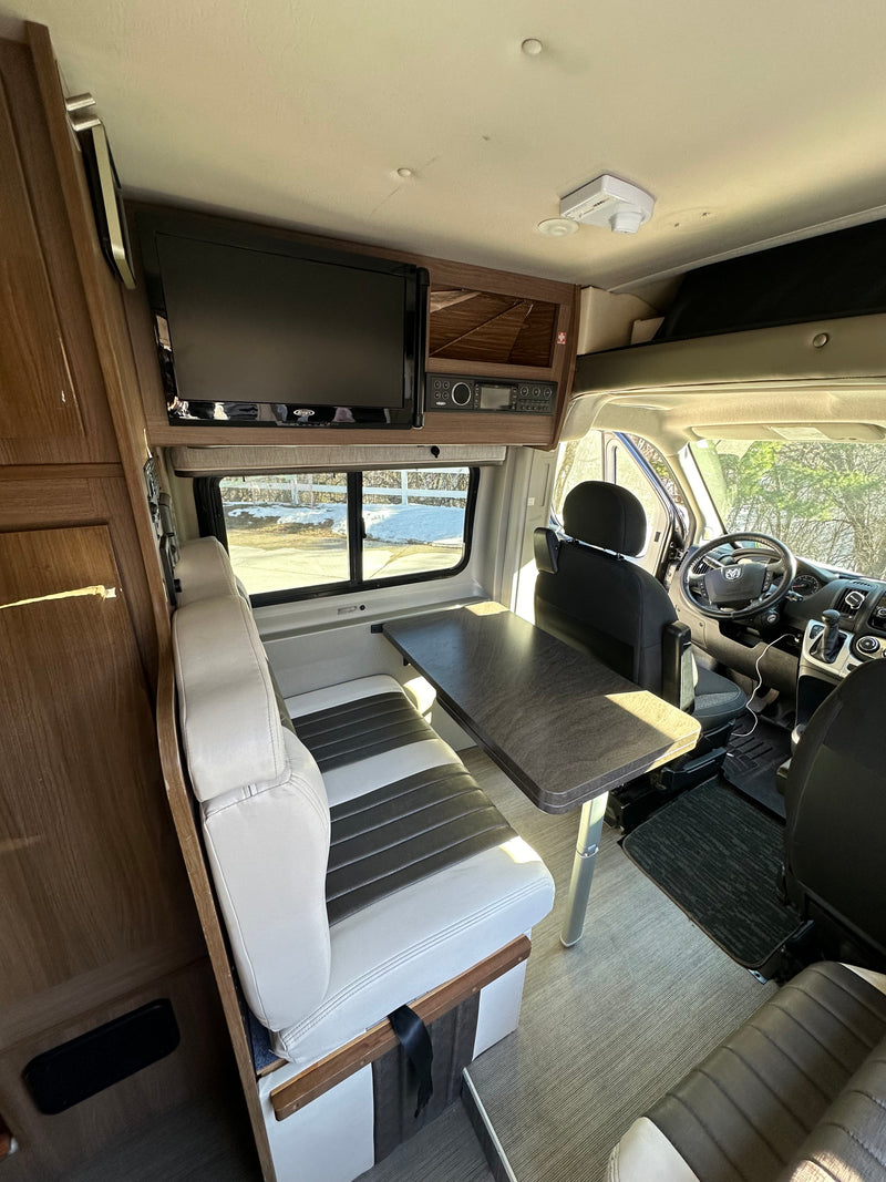 Inside an RV rental: view of the driver's area, dining booth with table, and overhead entertainment system. — photo 6