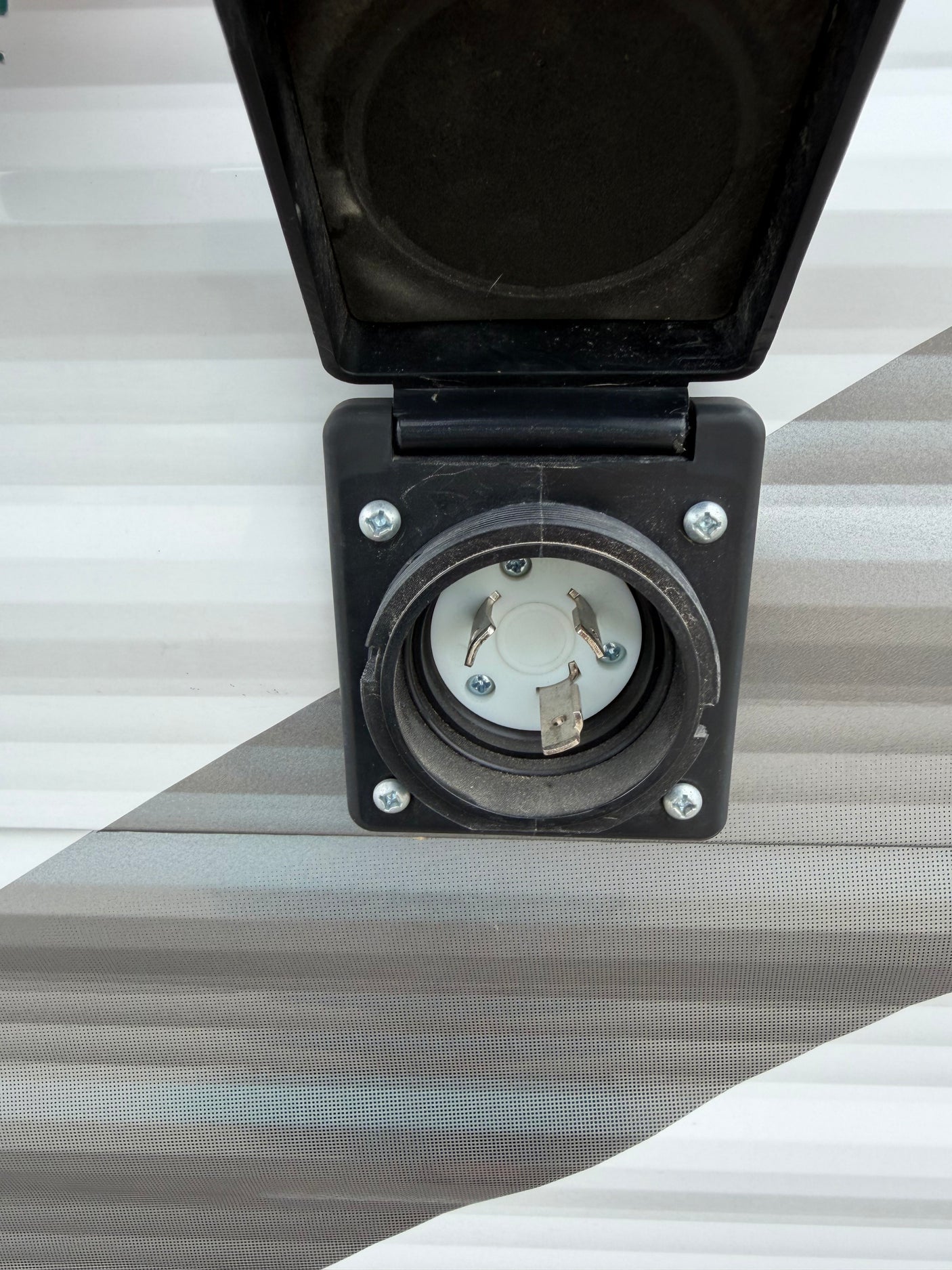 Close-up of a 30 Amp twist-lock shore power inlet on an RV rental, essential for connecting to campsite electricity.