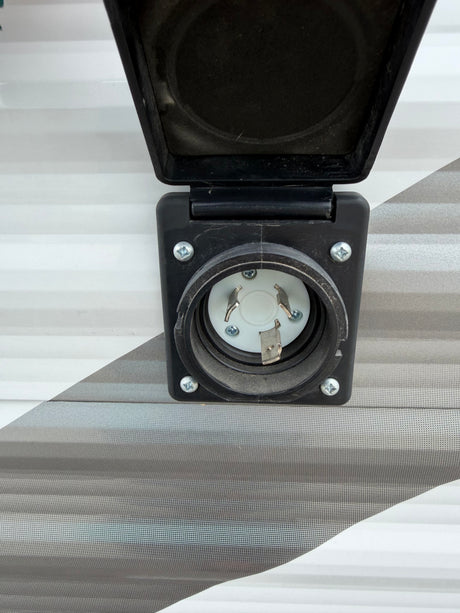 Close-up of a 30 Amp twist-lock shore power inlet on an RV rental, essential for connecting to campsite electricity.