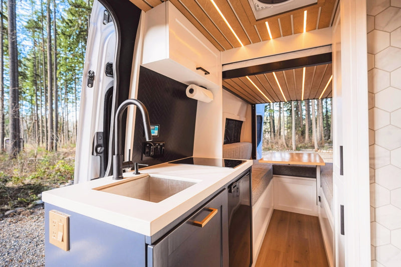 Inside a stylish rv rental: a well-equipped kitchen, comfortable dining space, and serene forest backdrop. — photo 2
