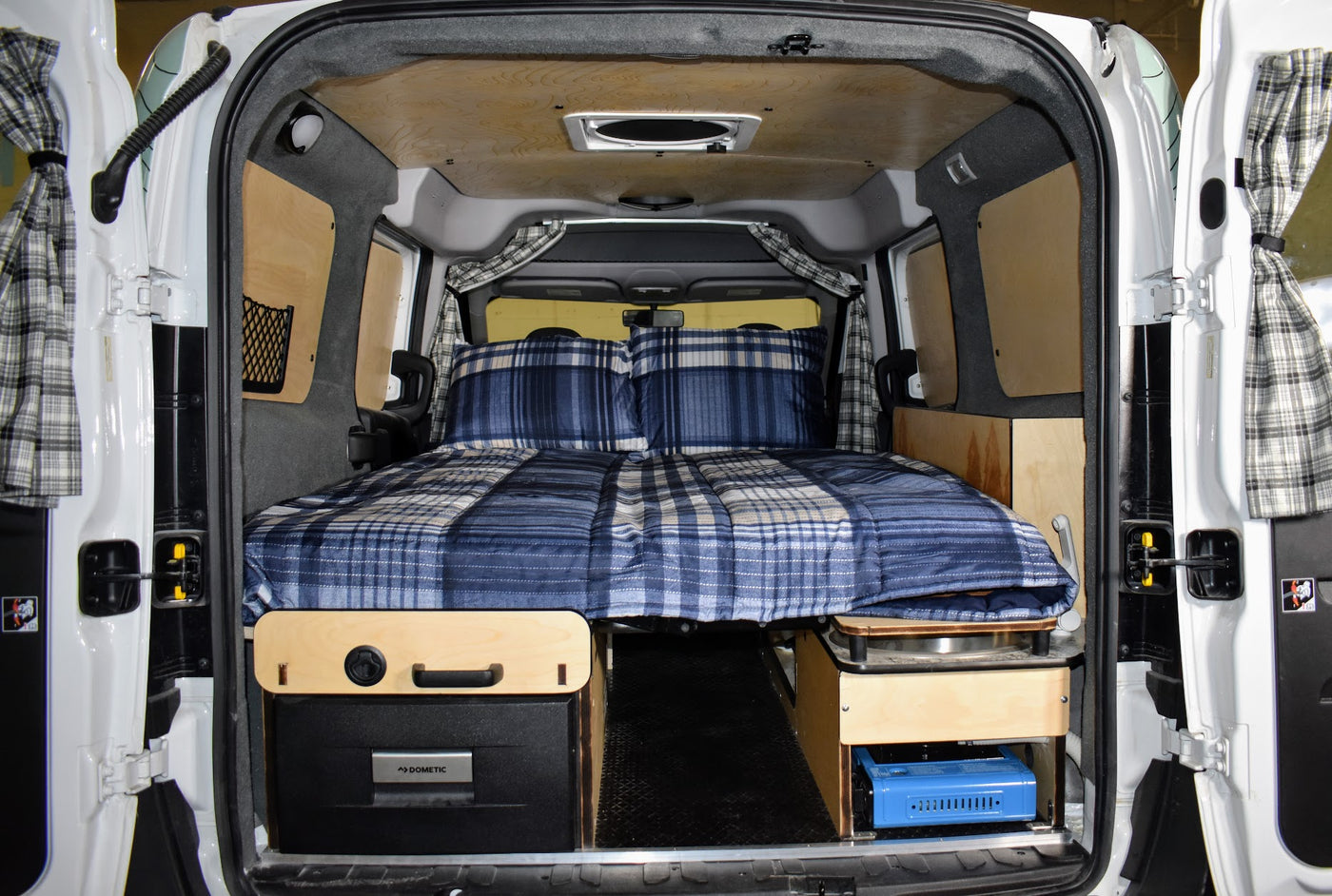 This RV rental boasts a comfortable bed, compact kitchen, and smart storage in its camper van interior. — photo 4