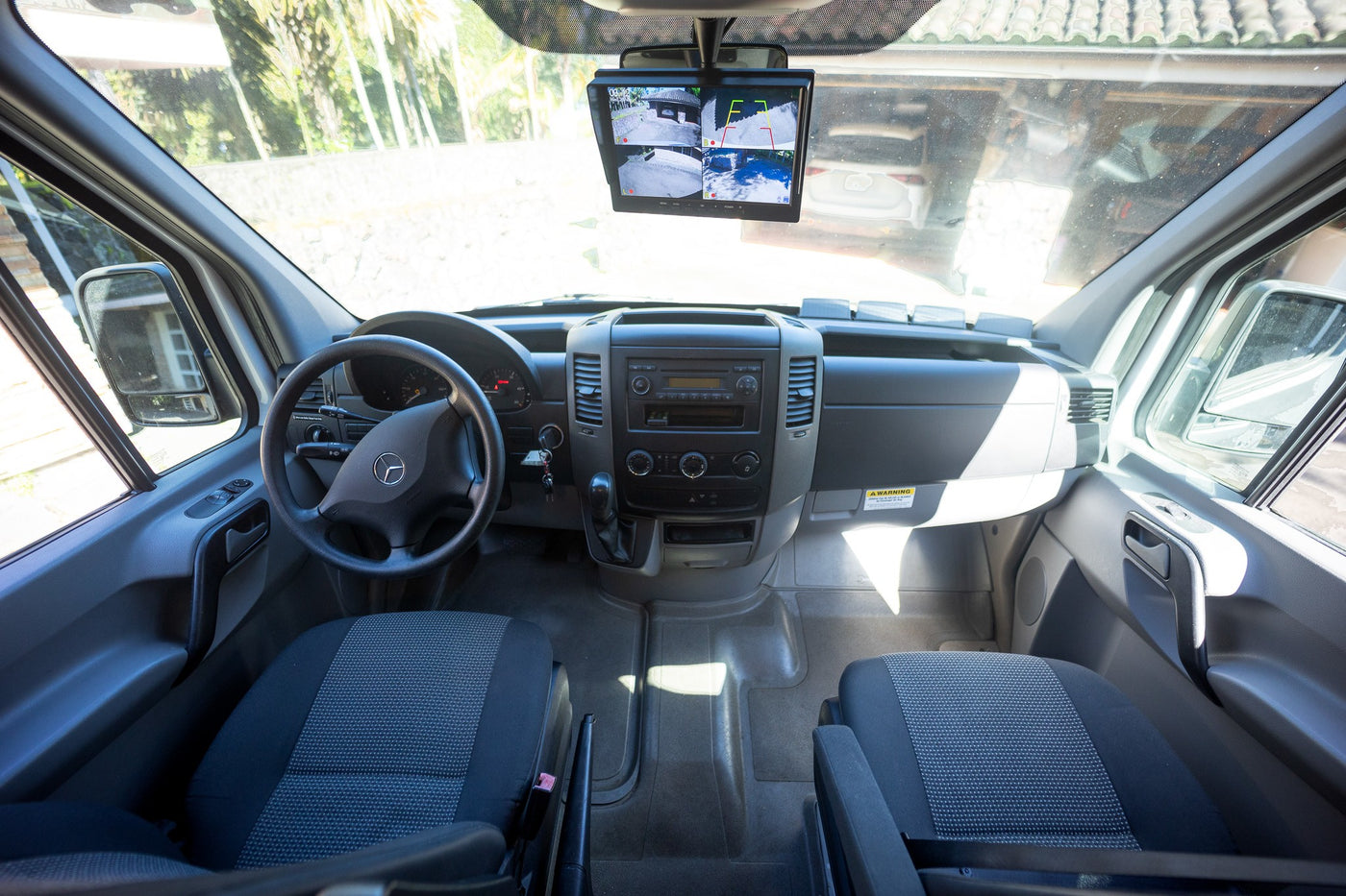 Interior of an RV rental van, highlighting the dashboard, steering wheel, and a monitor displaying multiple camera views for parking. — photo 16