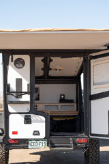 Open rear hatch of a TAXA Outdoors camper, an ideal rv rental for adventure. Shows organized mobile living space.