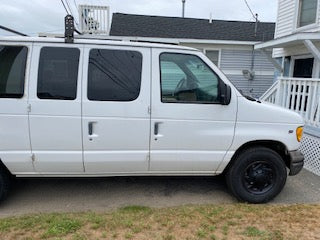 Side view of a white commercial vehicle with tinted windows & roof rack. Ideal for a cargo or rv rental service.