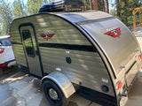 This compact, beige Retro Jr. travel trailer with Dometic AC is ready for your RV rental outdoor adventure.