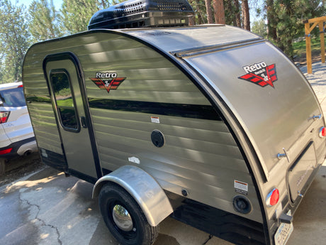 This compact, beige Retro Jr. travel trailer with Dometic AC is ready for your RV rental outdoor adventure.