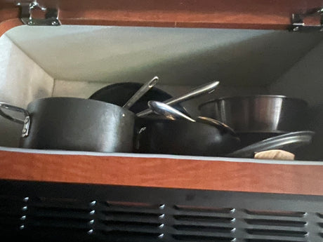 RV rental kitchen: pots and pans efficiently stored in a compact cabinet, ready for cooking adventure.