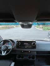 Driver's view from a Mercedes-Benz Sprinter RV rental: dashboard, steering wheel, and road outside.