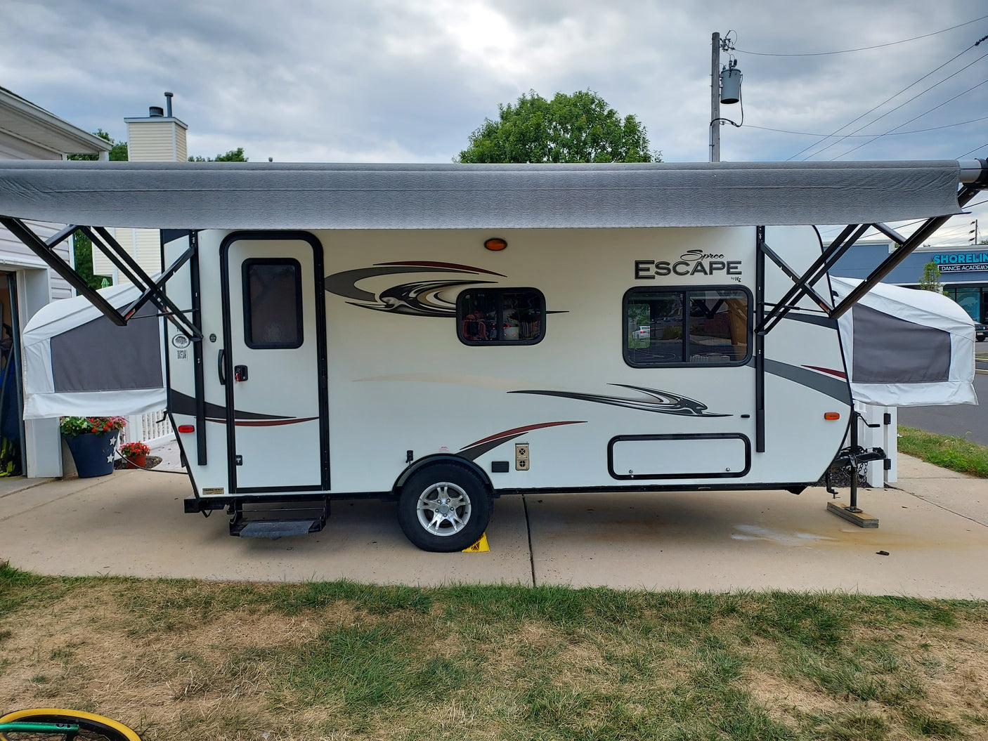 White Spree Escape pop-up RV rental with extended awning, parked on a driveway