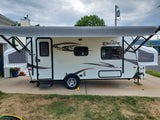 White Spree Escape pop-up RV rental with extended awning, parked on a driveway