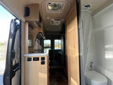 RV rental interior: From the open side door, see the compact kitchen area, appliances, and integrated wet bath.