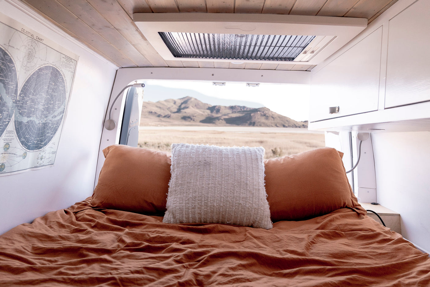 Relax in this cozy RV rental bed looking out at desert mountains. Features a celestial map & reading lamps for your journey.