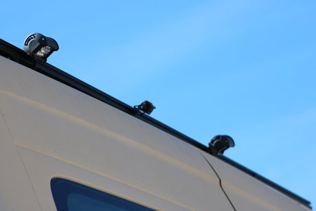 Auxiliary LED lights mounted on the roof of an RV rental van, with a clear blue sky background, enhancing visibility for travel.
