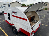 White and red "Retro Jr." teardrop RV rental with an open galley kitchen, sink, and stovetop. Perfect compact camping.