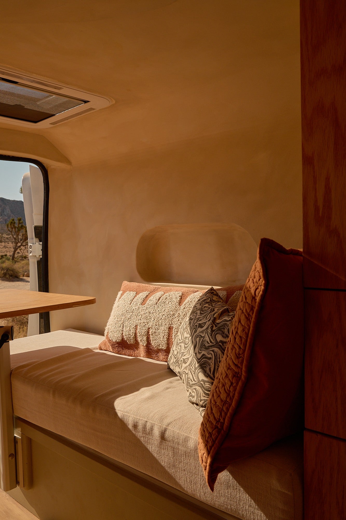 Cozy rv rental interior with desert views. Bench seating, warm light, and comfy cushions create an inviting camper van space.
