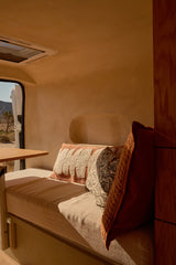 Cozy rv rental interior with desert views. Bench seating, warm light, and comfy cushions create an inviting camper van space.