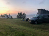 Enjoying a beautiful sunset by the ocean in an RV rental, with a cool boat nearby. Perfect for camping!