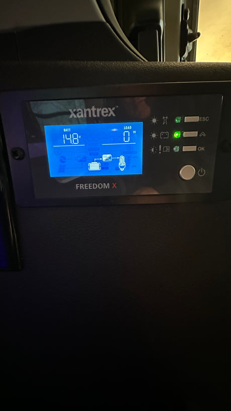This Xantrex Freedom X inverter display in an RV rental shows 14.8V battery and 0W load, monitoring the electrical system in a camper.