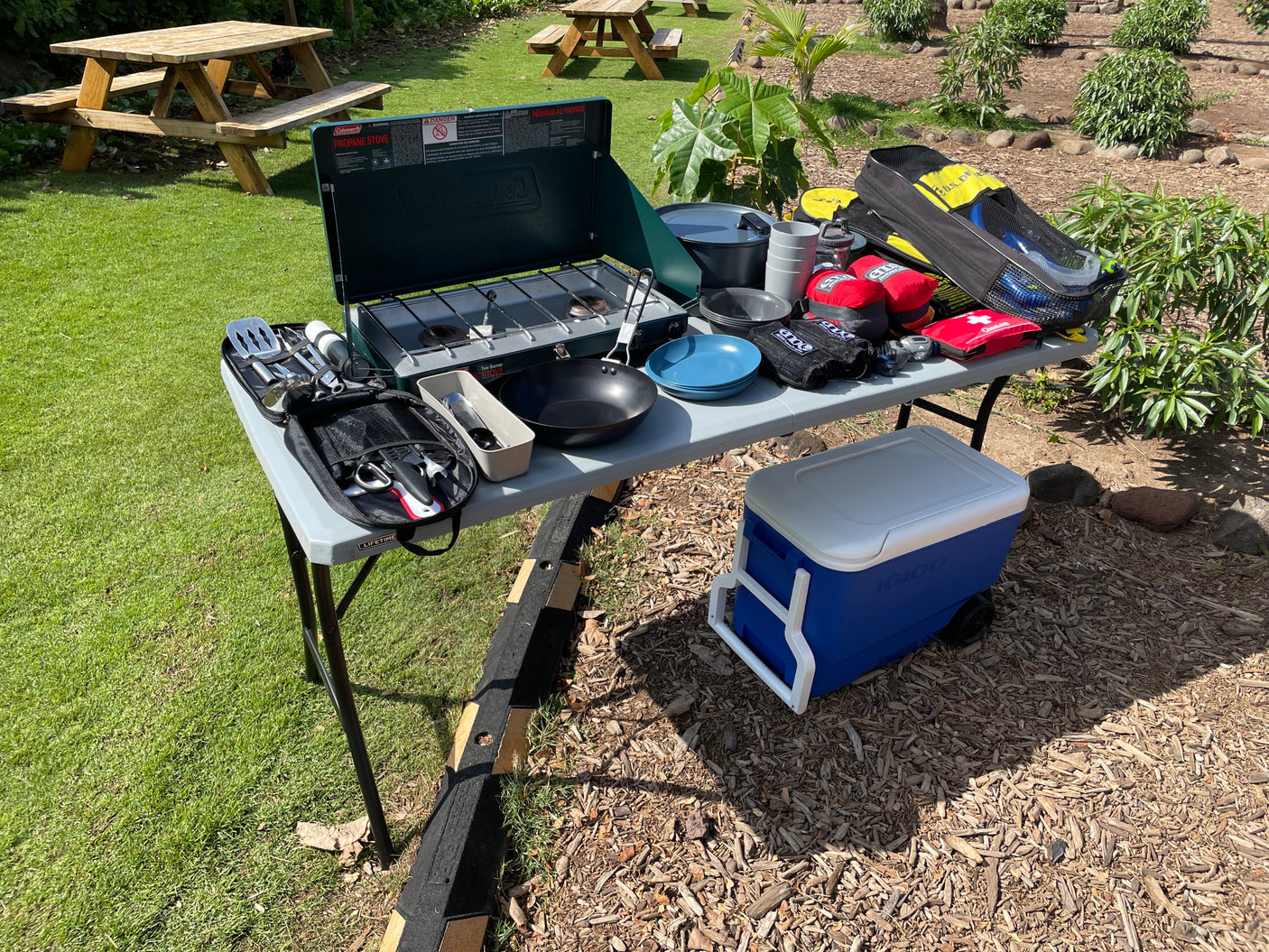 RV rental ready! Coleman stove, Igloo cooler, and camping gear laid out on a table for outdoor cooking and adventure.