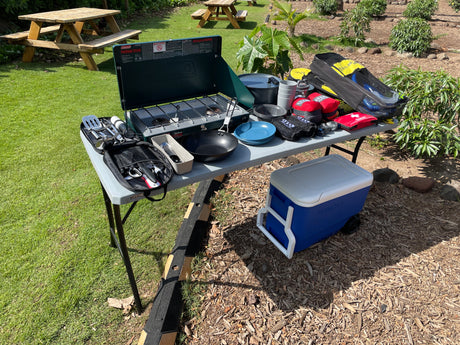 RV rental ready! Coleman stove, Igloo cooler, and camping gear laid out on a table for outdoor cooking and adventure.