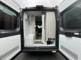 Open rear doors of an RV rental show a compact interior with a shower, toilet, and seating area. Ideal for travel.