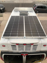 Overhead view of an RV rental's roof, featuring multiple solar panels and a central vent for off-grid power.