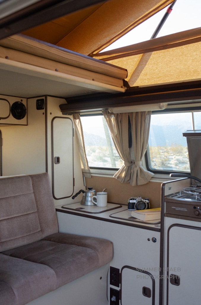 Inside a classic pop-top RV rental: cozy seating, a compact kitchen with coffee, and desert views. Ideal for travel! — photo 3