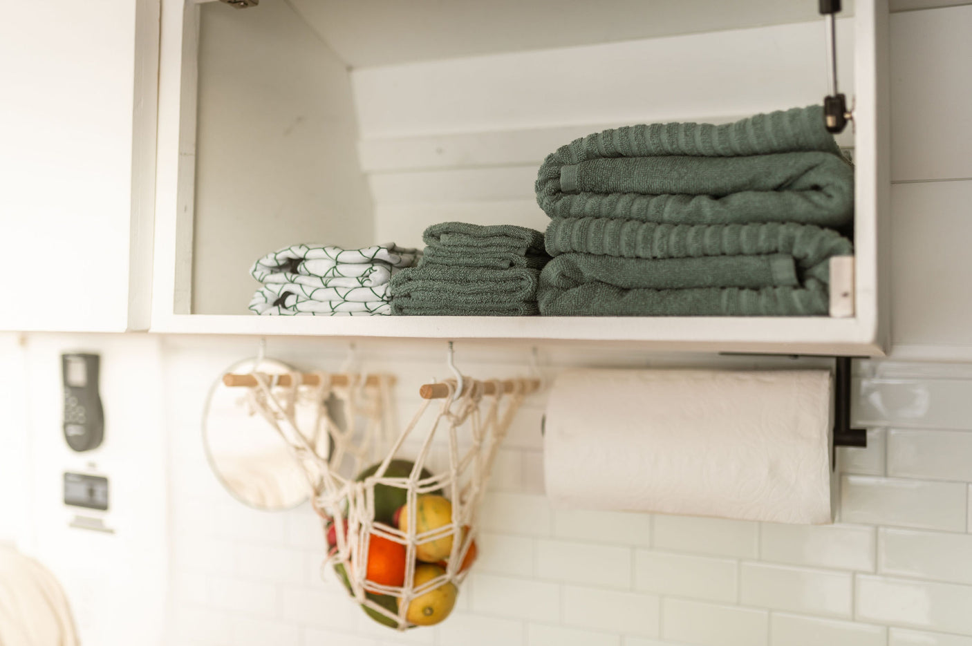 Smart storage in an RV rental: neatly folded towels, kitchen paper, and fresh fruit in a compact, organized space.