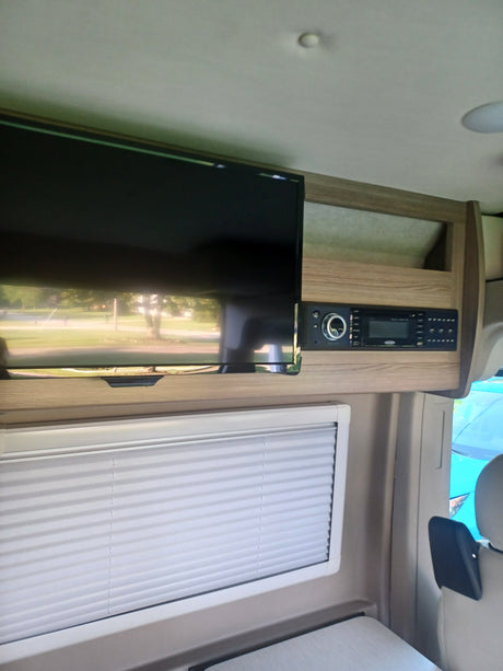 This RV rental features a flat-screen TV, an electronic control panel, and a pleated window blind.