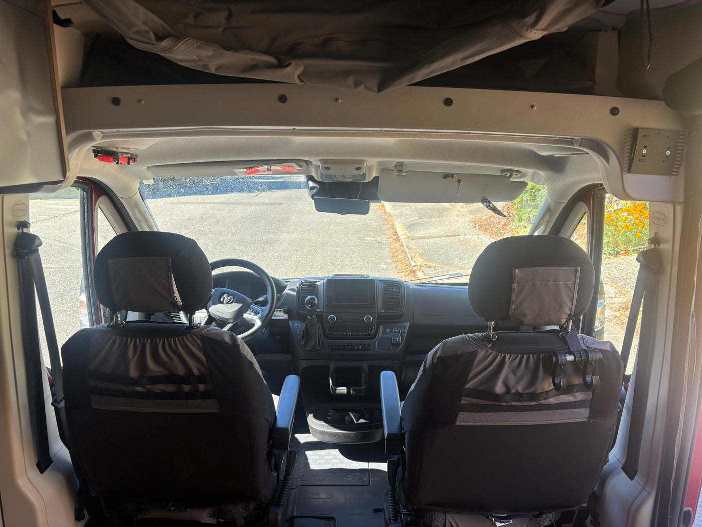 View of an RV rental van's front cabin from the back, highlighting seats, dashboard, and the road ahead.
