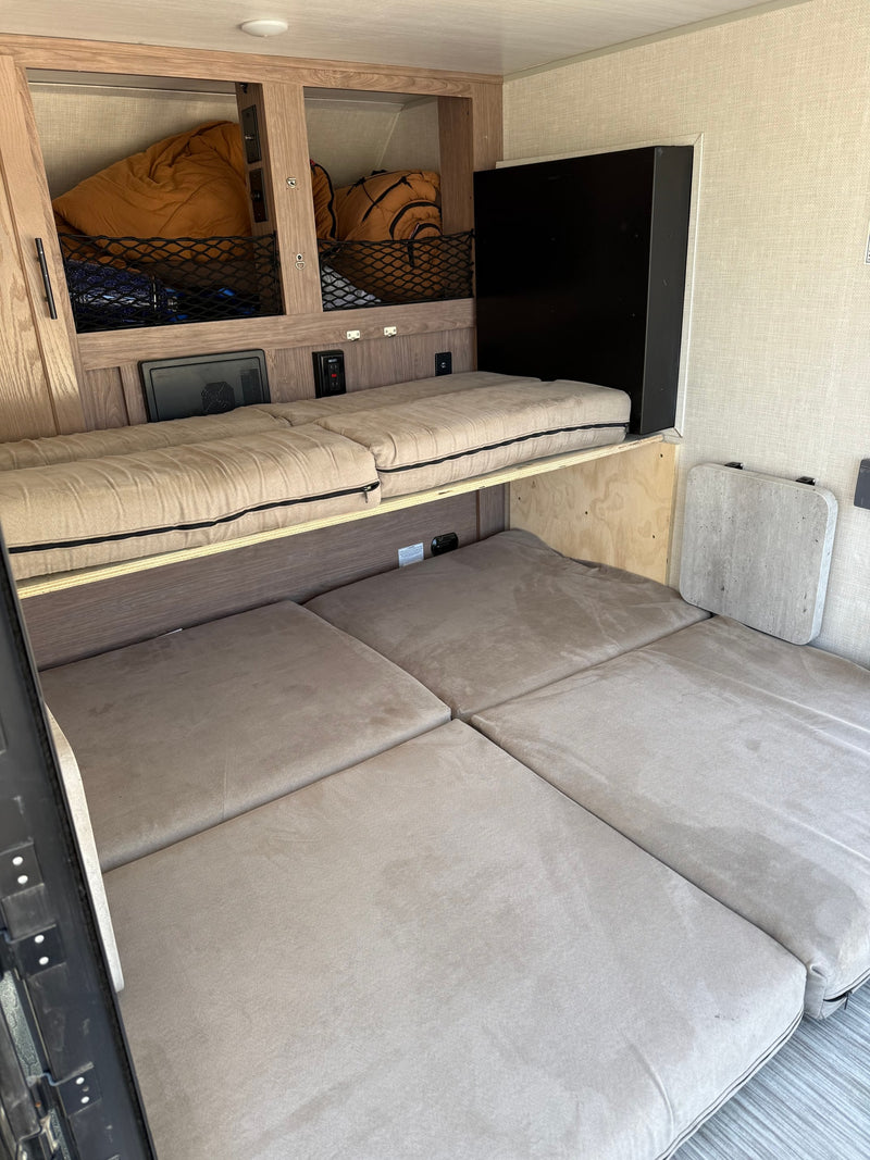 RV rental interior featuring upper and lower bunk beds, built-in storage nets, and a wall-mounted table. — photo 3