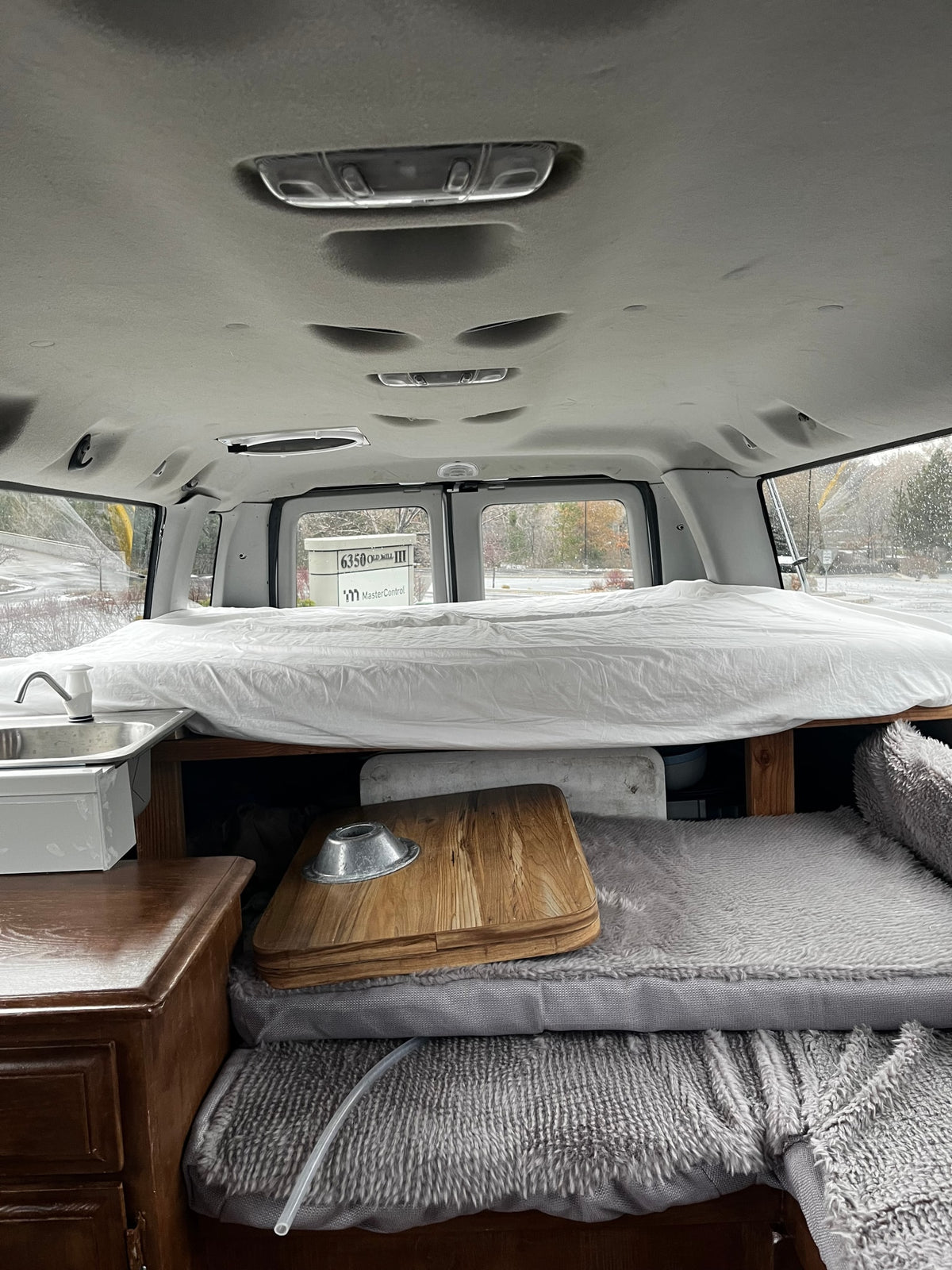 Cozy RV rental interior: bed, sink, and storage in a custom camper van conversion. Perfect for mobile living. — photo 9