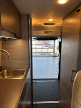 RV rental: Spacious camper van interior featuring a modern kitchen with sink, cozy bunk bed, and rear garage access.